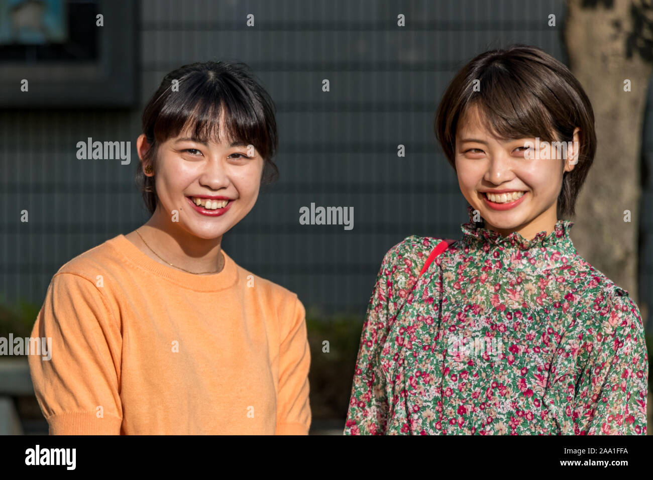 Portrait of two Japanese young women smiling looking camera, nihonjin ethnicity, outdoors in Kanawawa, Japan Stock Photo