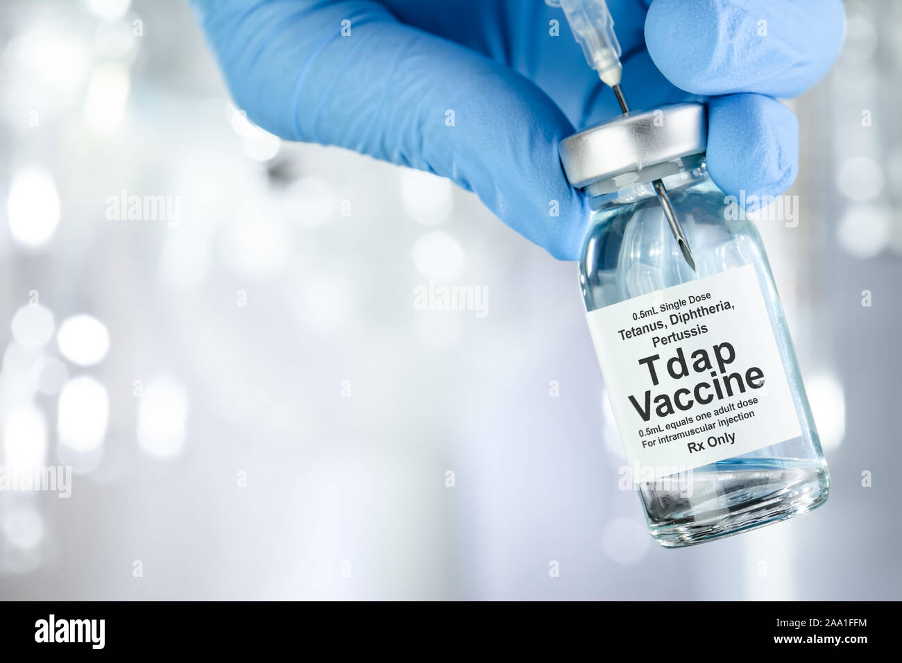 Healthcare concept with a hand in blue medical gloves holding Tap, tetanus, diptheria, and pertussis, vaccine vial Stock Photo
