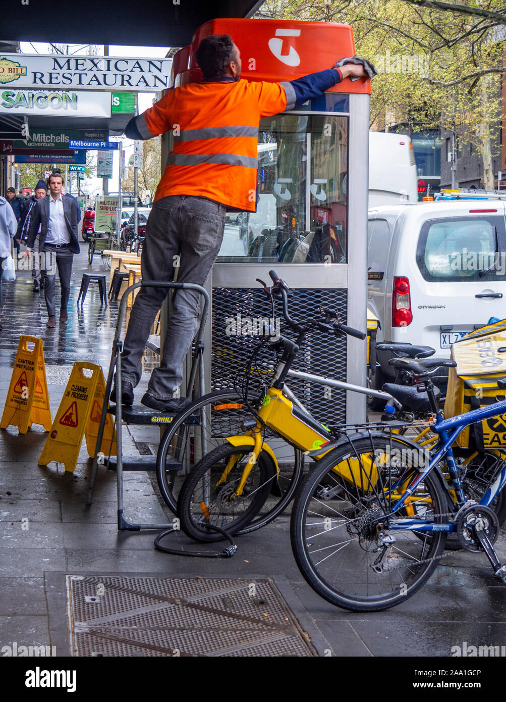 Cleaner cleaning a Telstra telephone booth on Russell St Melbourne