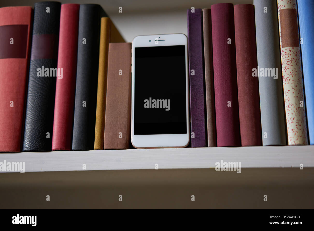 Close up of mobile phone in bookshelf, low angle Stock Photo