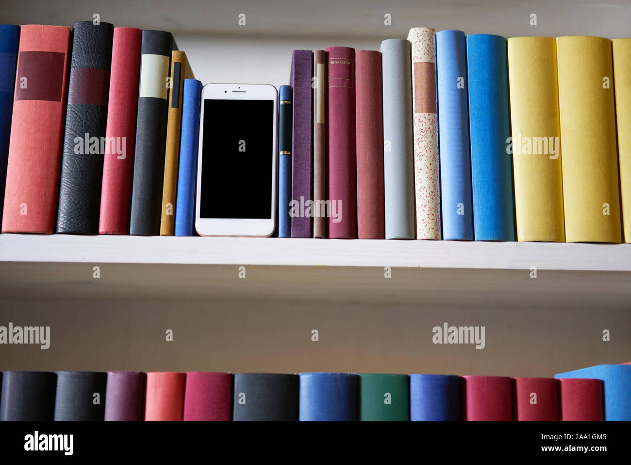 Close up of mobile phone in bookshelf, low angle perspective Stock Photo