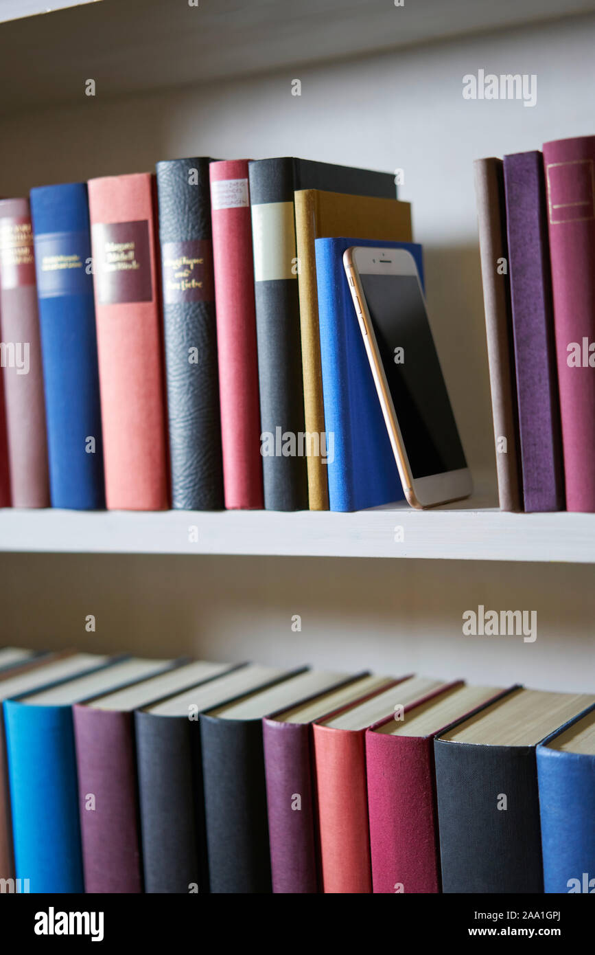 Upright format of bookshelf with new mobile phone Stock Photo