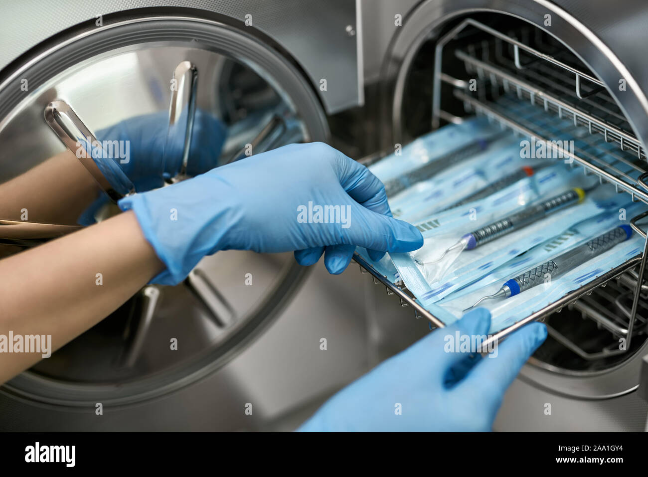 Dentist in blue latex gloves is taking a sealed dental probe from an