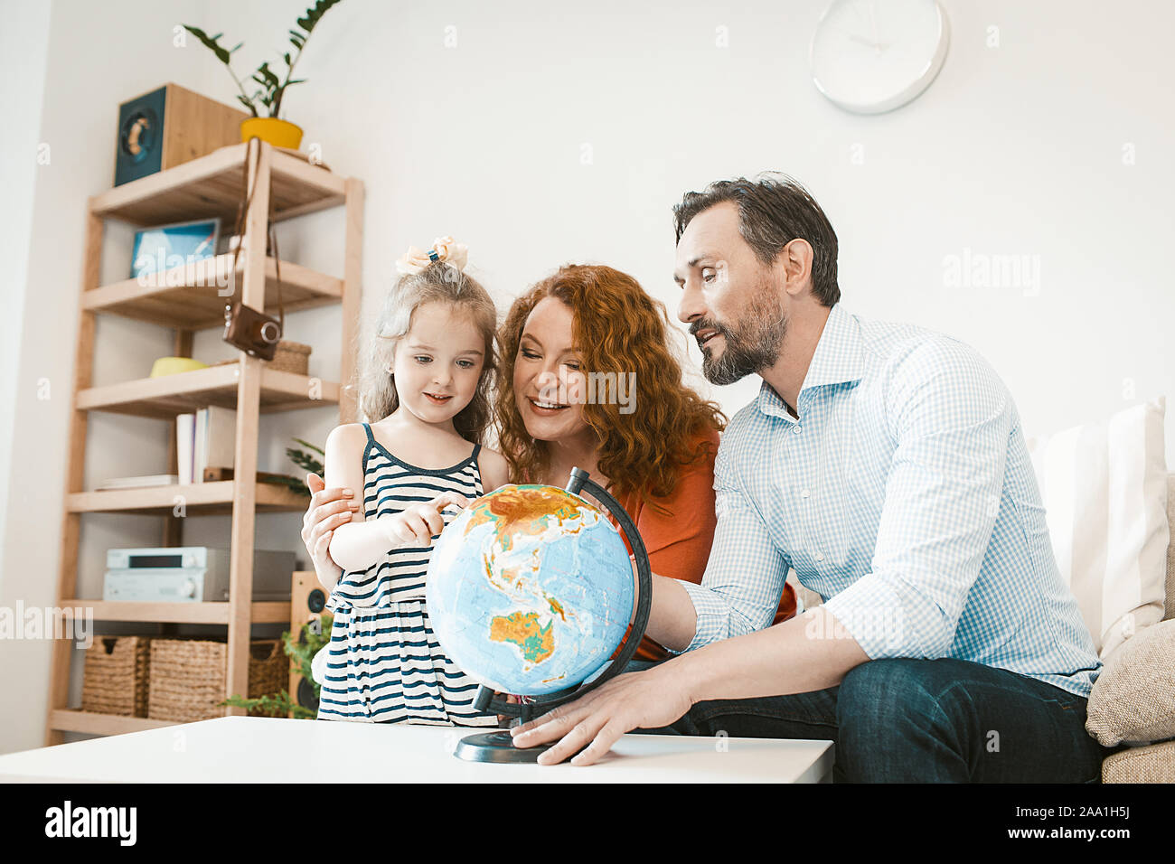 Planning vacation, parents and little daughter studying globe. Stock Photo