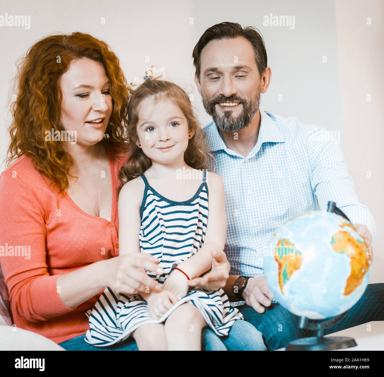 Mom, dad and little daughter studying globe. Stock Photo