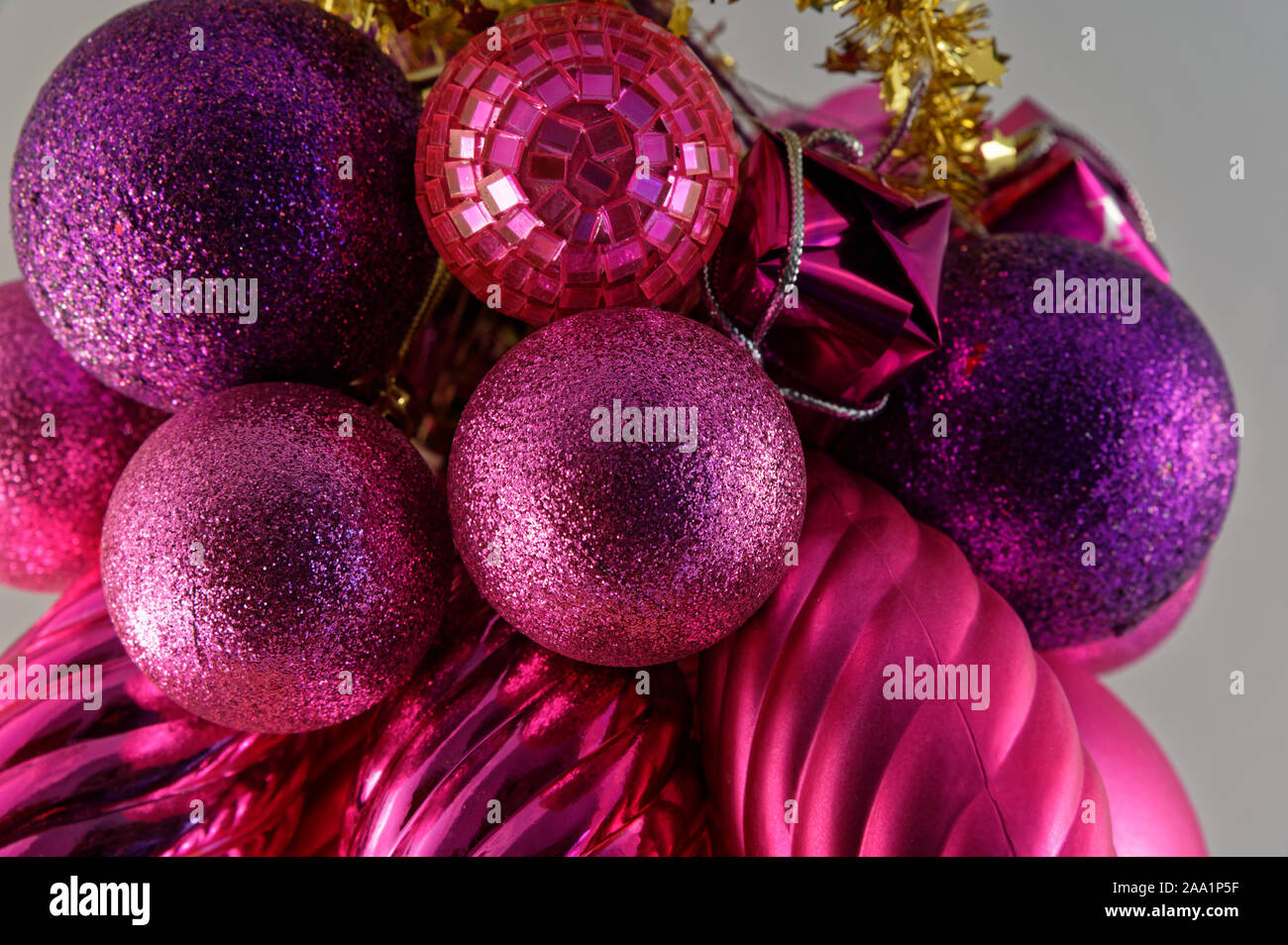 Purple and red Christmas decorations with gold tinsel on a grey background Stock Photo