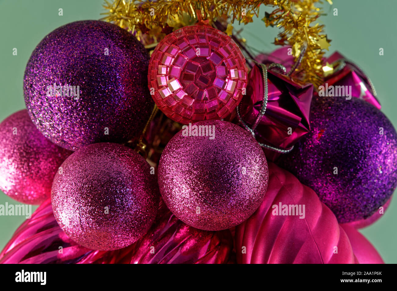 Purple and red Christmas decorations with gold tinsel on a green background Stock Photo