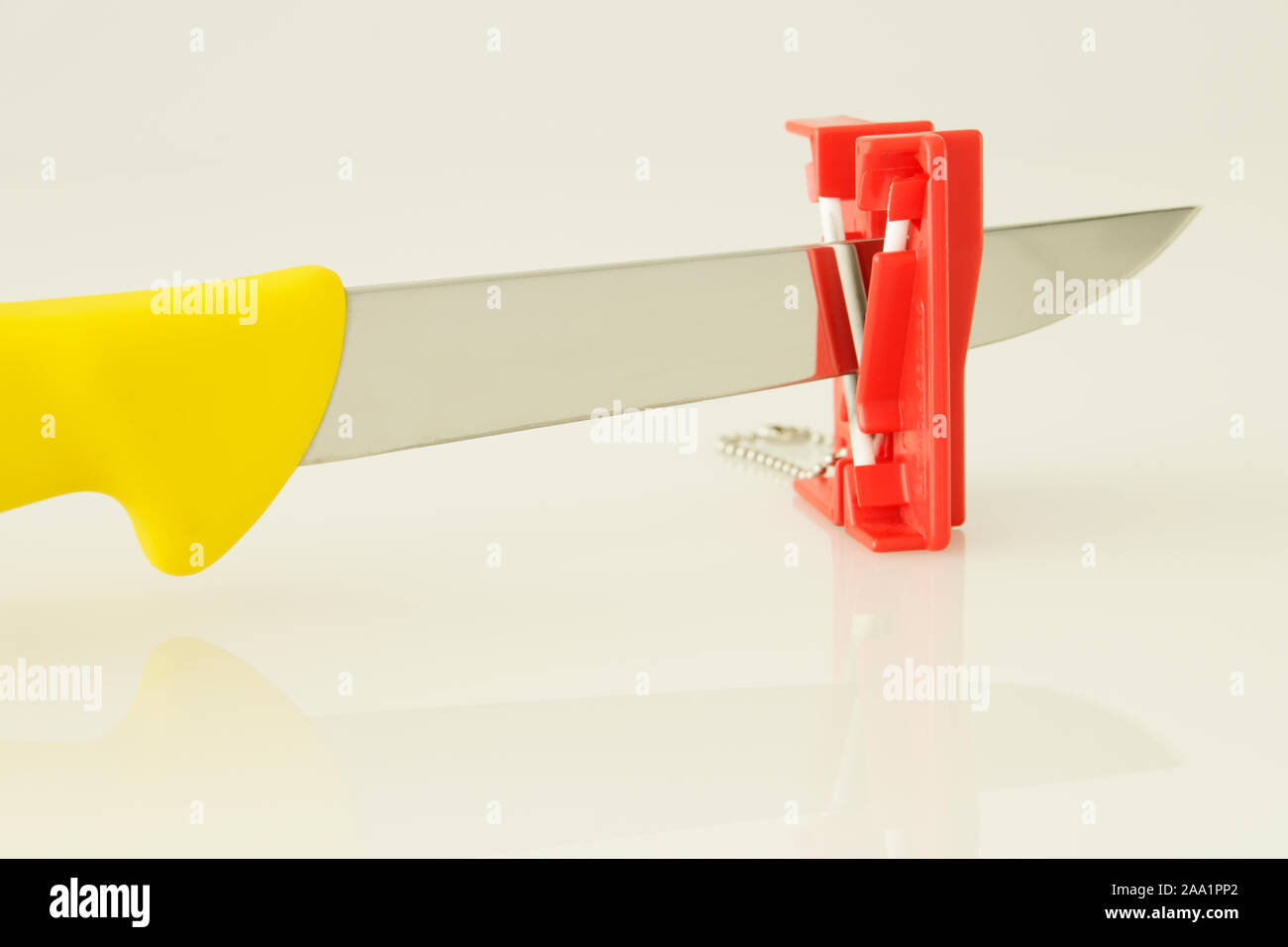 Sharpening deboning kitchen knife on mini whetstone, tool, objects, close up, concept, idea, high key background Stock Photo