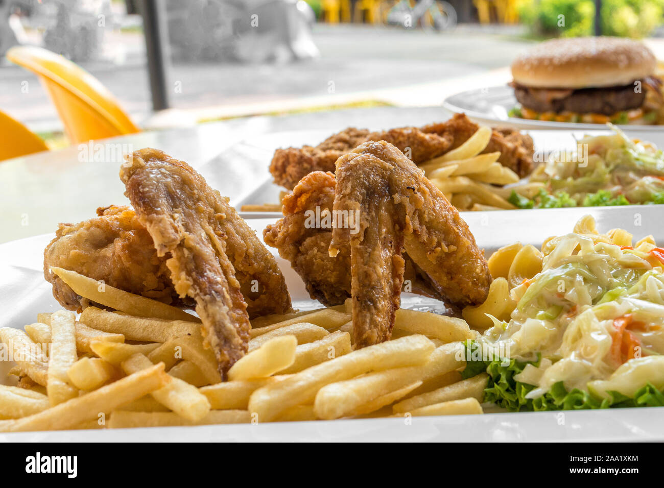 Closeup detailed view of two pieces of fried chicken wings, french fries, Mac & Cheese and
