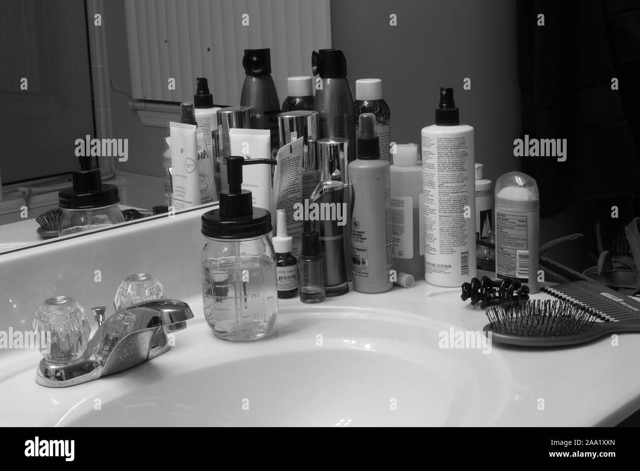 Bathroom sink counter with various shampoos, lotions, soaps, perfumes, and toiletries Stock Photo