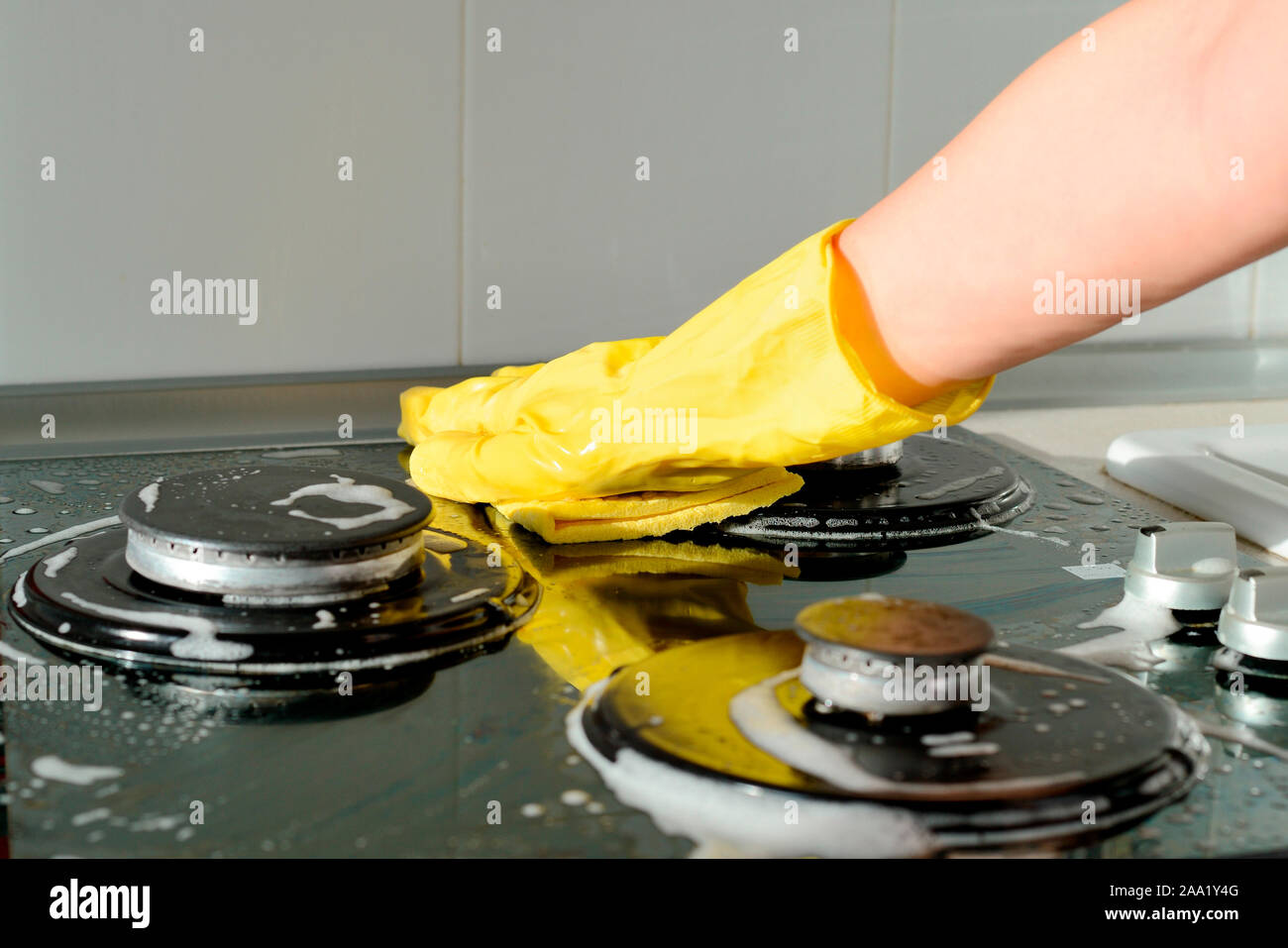 In A Yellow Rubber Glove A Hand Cleans A Gas Stove Kitchen