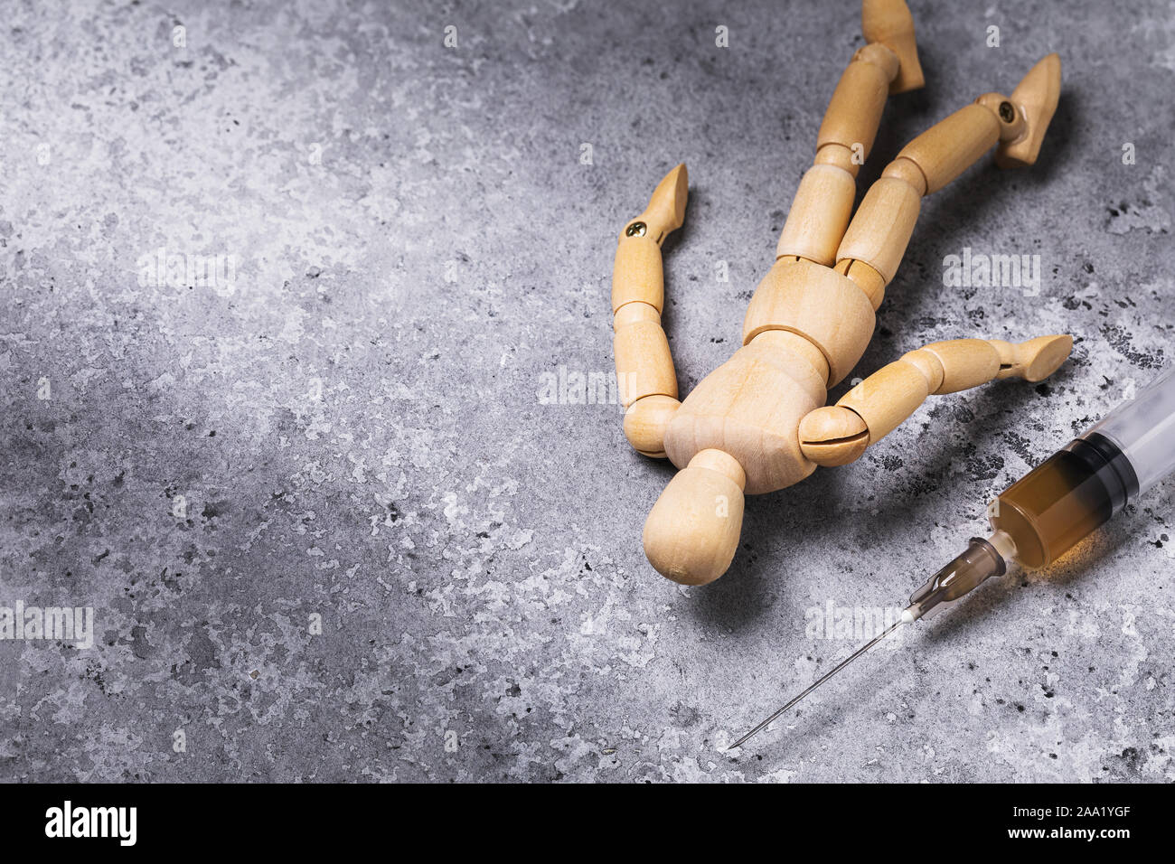 A syringe with drugs and next to it lies the figure of a man made of wood. Addict on the floor. Concept on the topic of drug withdrawal with copy spac Stock Photo