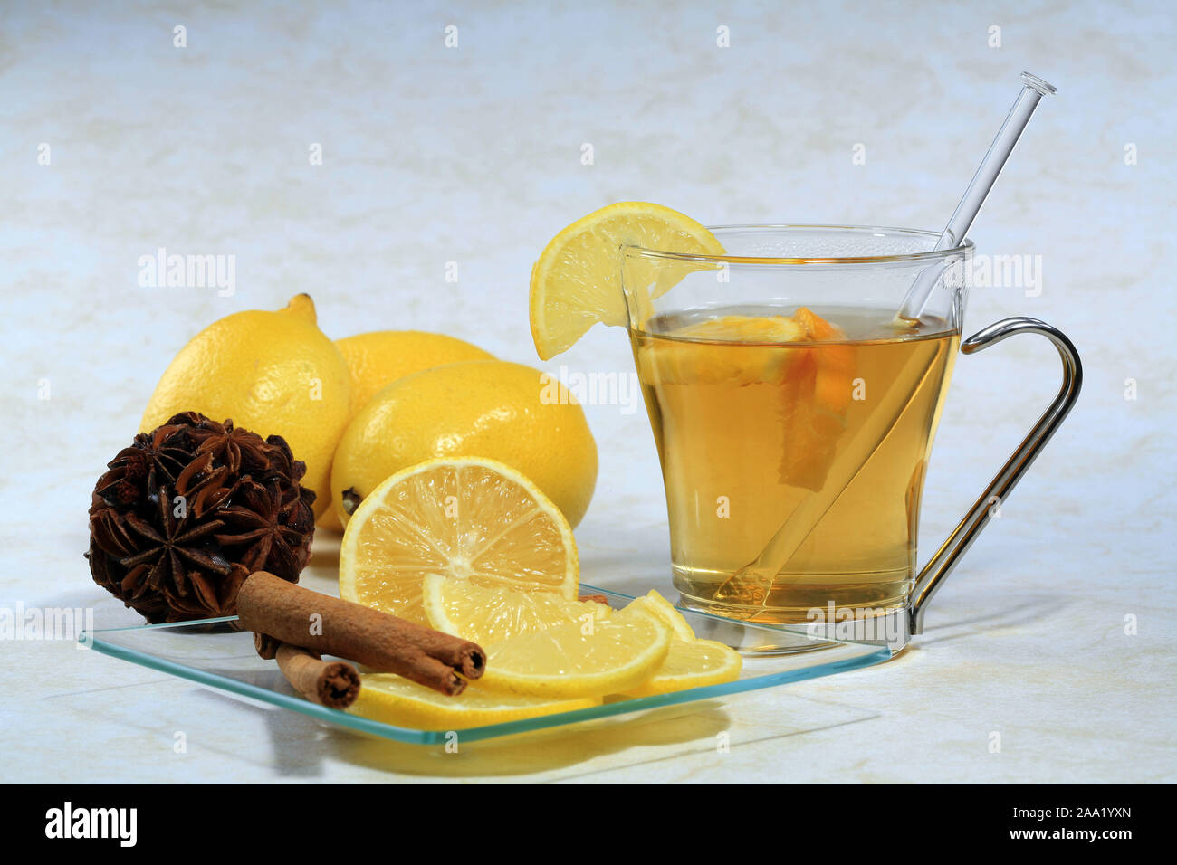 Eine Tasse Tee  mit Zitronen, Nelken  und Zimtstangen auf einem Glasteller / A cup of tea with lemon, cloves and cinnamon sticks on a glas plate Stock Photo