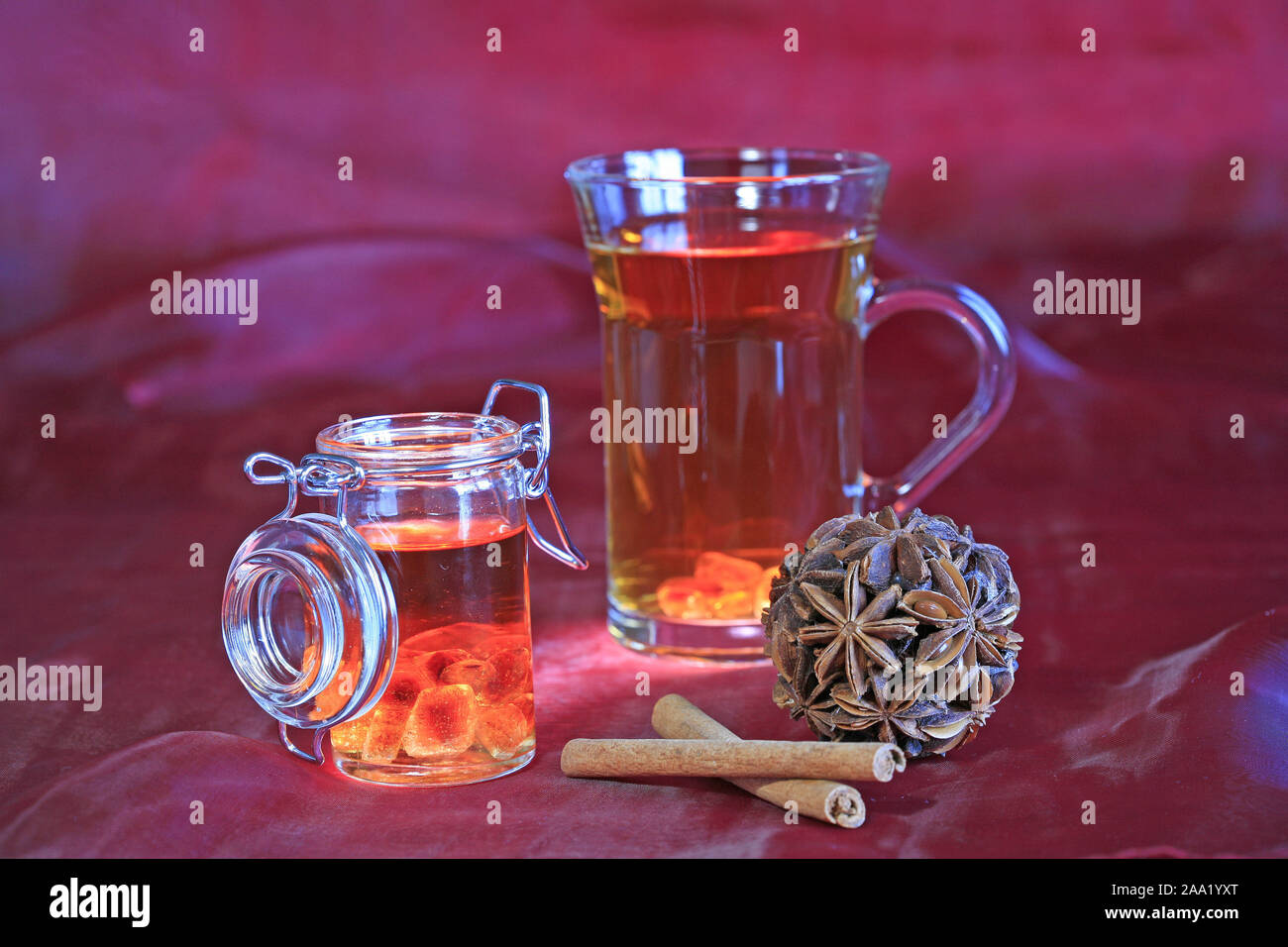 Eine Tasse Tee  mit einem verschlieﬂbarem Glas mit Rum-Kandiszucker, Nelken und Zimtstangen / A cup of tea with a lockable glas of rock candy in rum, Stock Photo