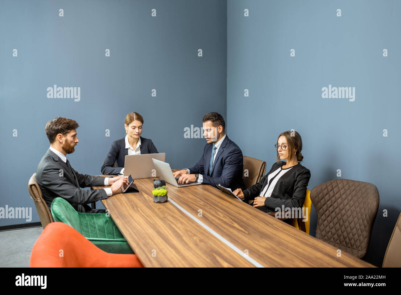 Group of business people strictly dressed in the suits sitting at the big table during a conference in the meeting room Stock Photo