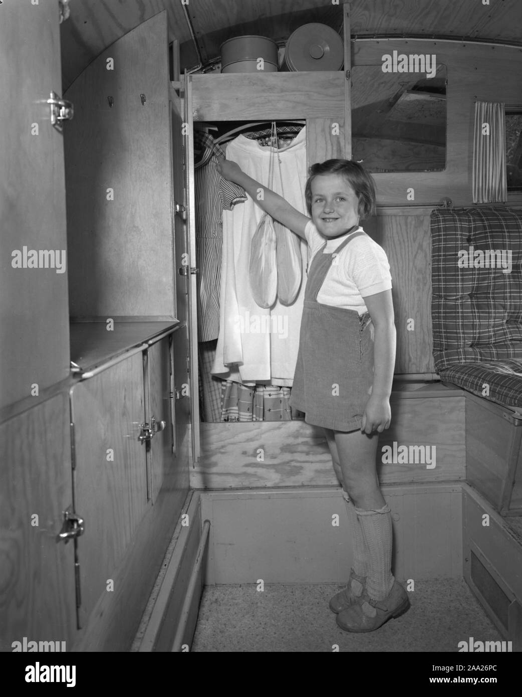1950s camping. A family is enjoying their holiday and the practial camping life in their caravan. Demonstrating how well everything works for them even on holiday. The daughter in the family demonstrates the practical closet where clothes and other items are stored away. Sweden 1952 Ref 2021 Stock Photo