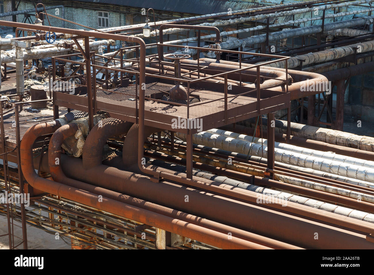 Old rusty pipelines at a chemical plant. Old factory. Industrial photography. Old factory horizontal photography. Metal planks and pipes. Stock Photo