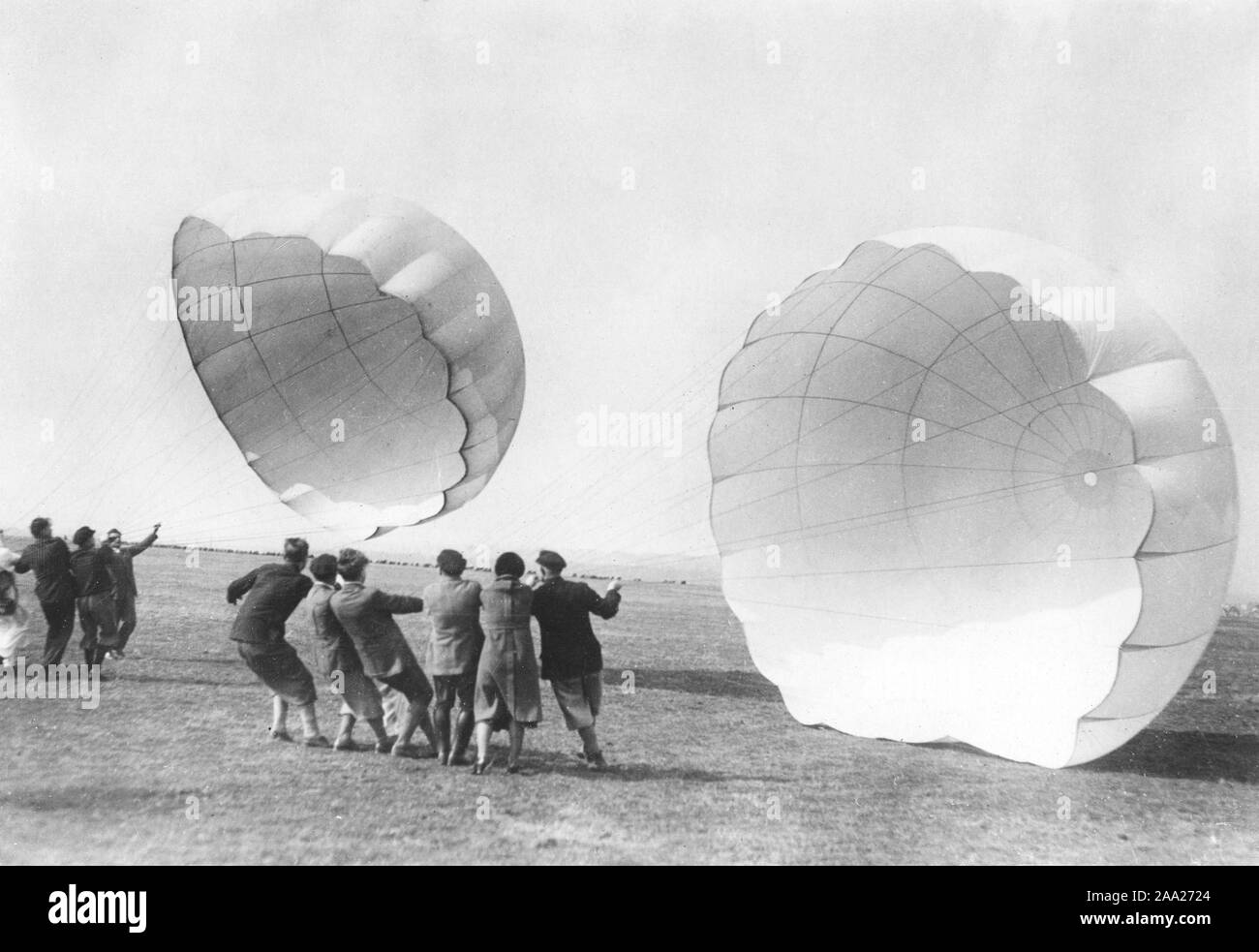 Parachute training in the 1930s. A school for parachuters to be are training and getting to know how a parachute works. They try their parachute and hold them against the wind. Germany 1930s Stock Photo