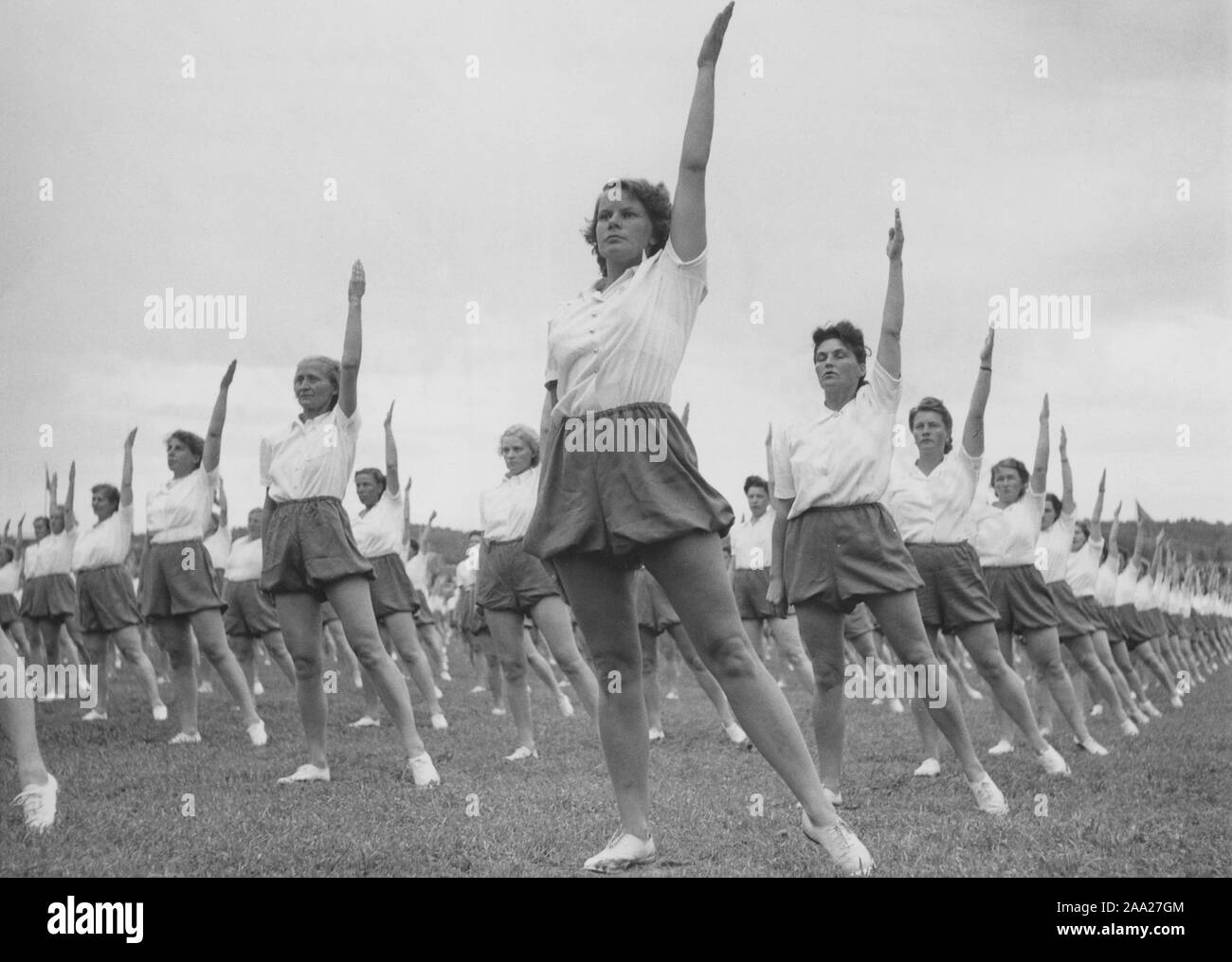 Gymnastics in the 1940s. The popular womens housewife gymnastics is being practiced everywhere. In the 1940s the knowledge on physical exercise encreased and the need of being active, both women and men.  Here a large number of women exercising together outdoors. Sweden 1949 Stock Photo