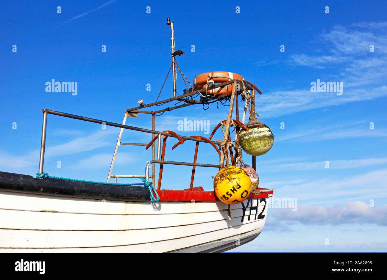 The stern of an inshore fishing boat with buoys and anchors on a North Norfolk beach at Cley-next-the-Sea, Norfolk, England, United Kingdom, Europe. Stock Photo
