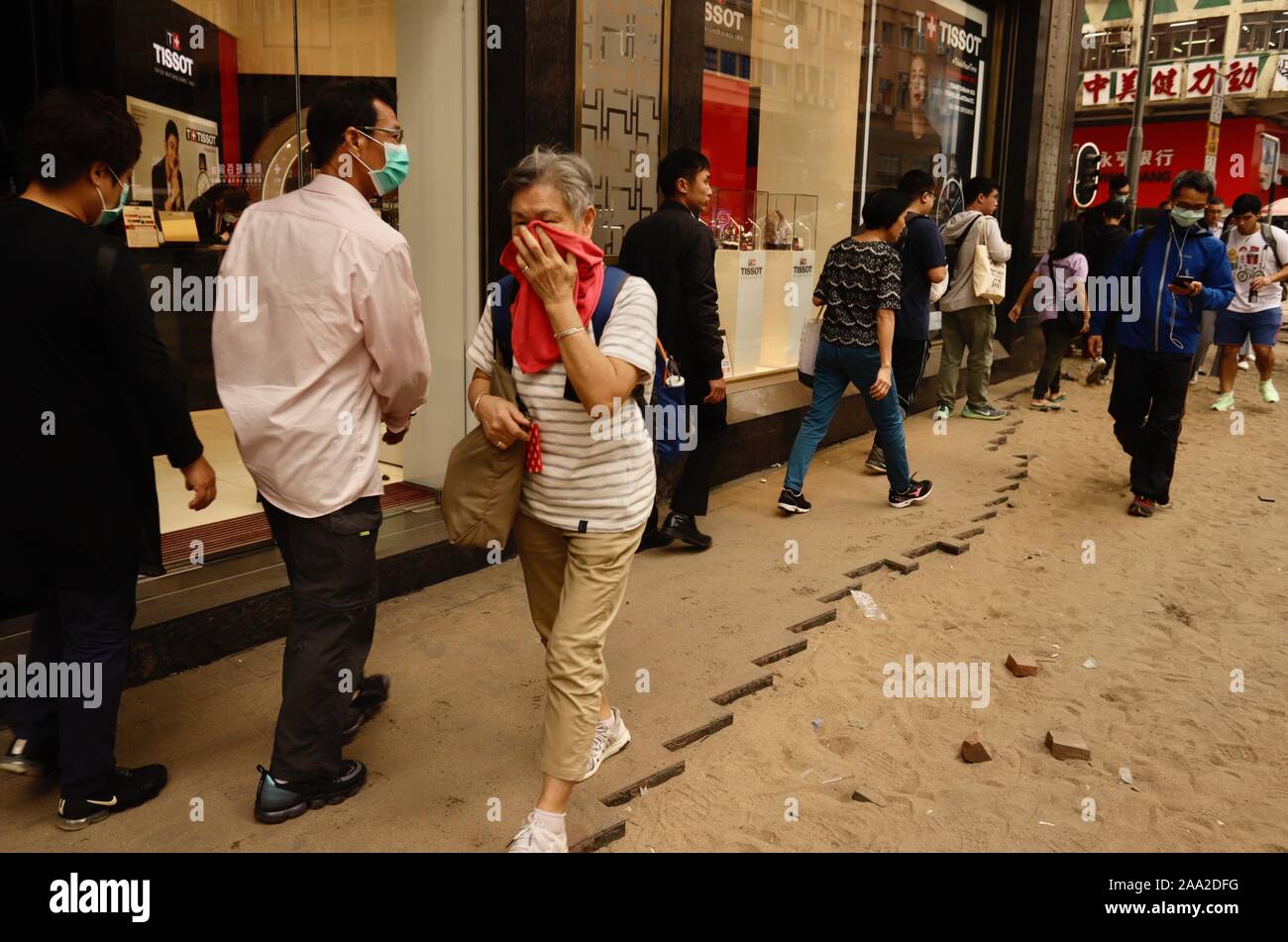 Hong Kong, CHINA. 19th Nov, 2019. Woman walk through a narrow strip of  broken pavement covering her nose from the polluted air at Jordan  junction.Thousands of round of tear gases were fired