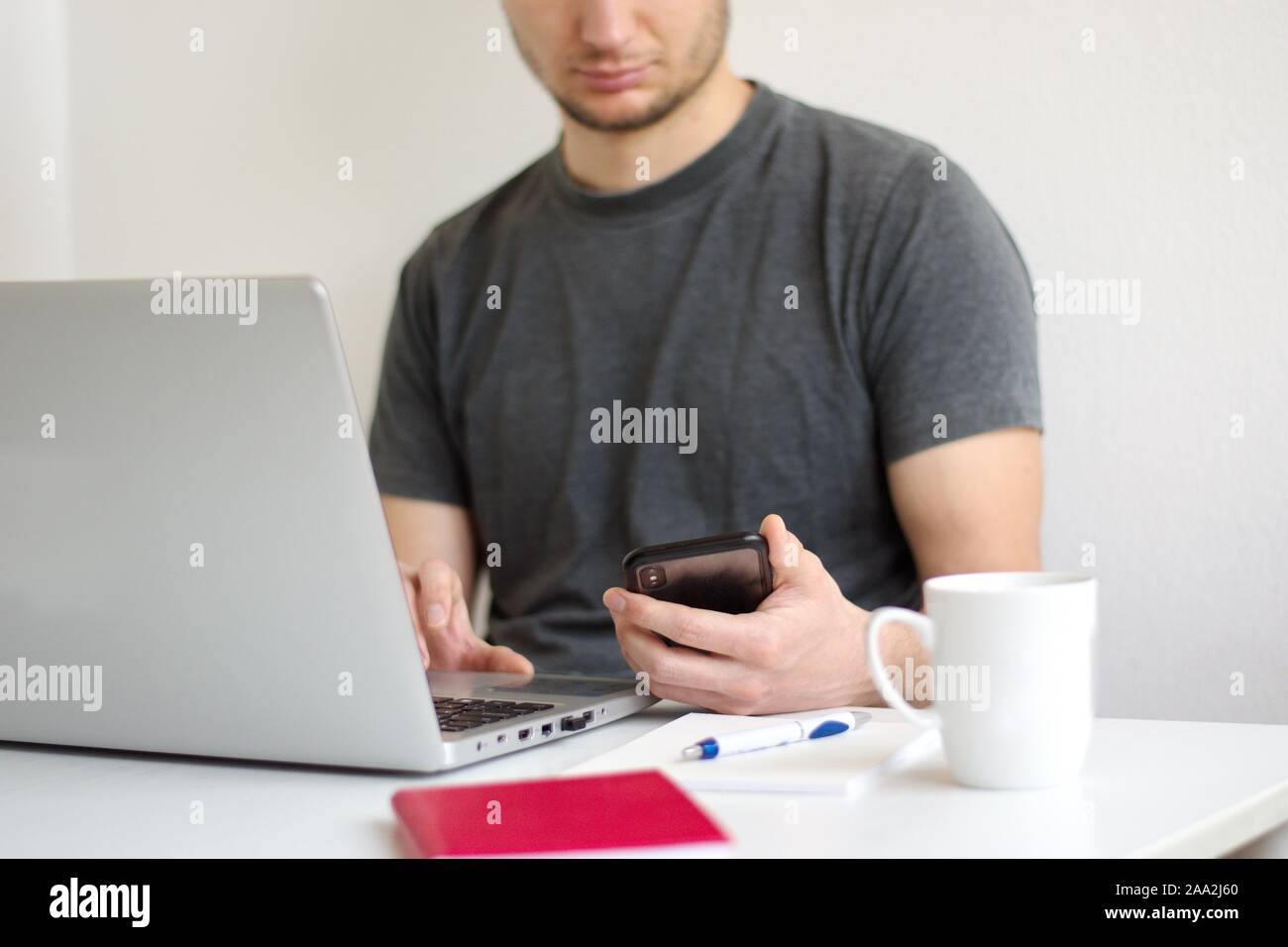 Young man sitting at the table using laptop Stock Photo