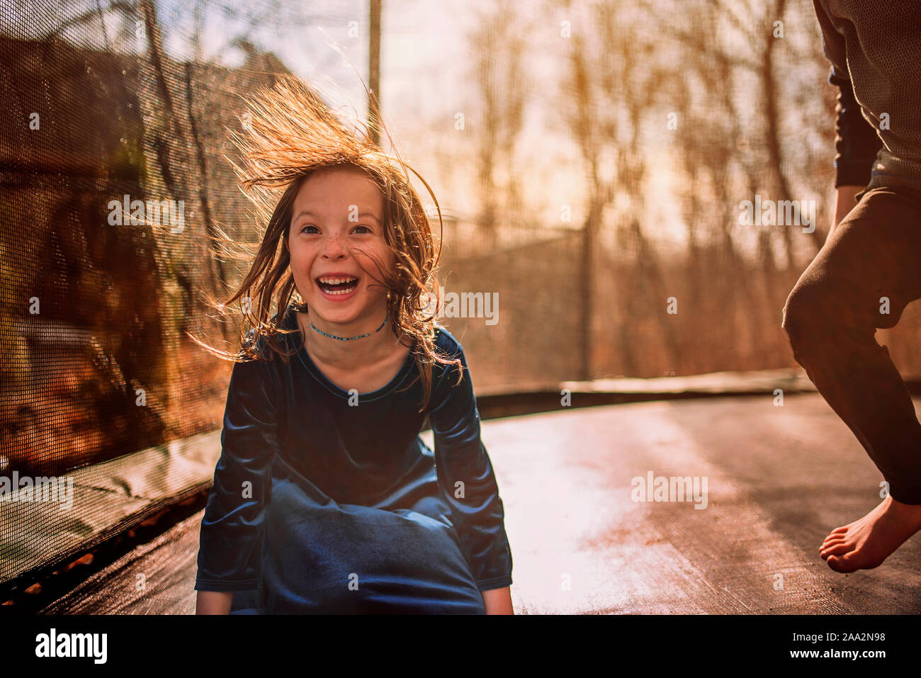 Smiling girl on a trampoline with her brother, USA Stock Photo