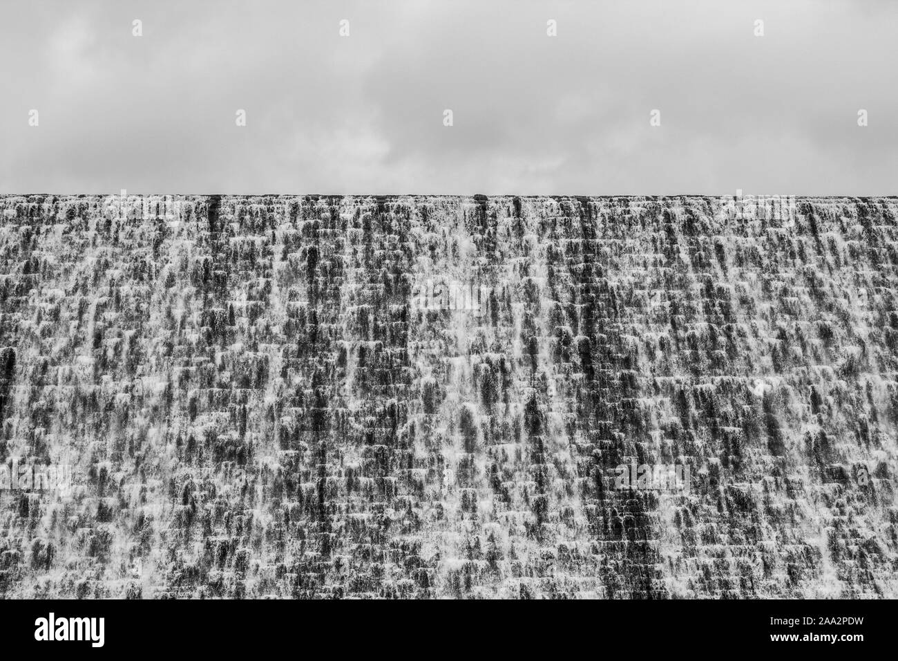 Back and white picture of the dam wall with water overflowing Ladybower reservoir, Peak District, Derbyshire Stock Photo