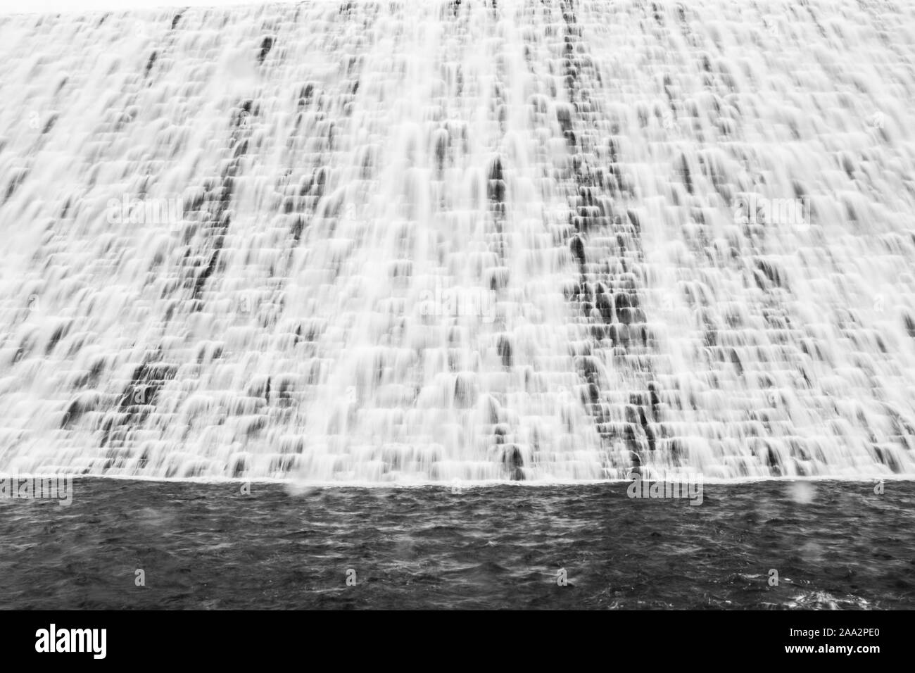 Back and white picture of the dam wall with water overflowing Ladybower reservoir, Peak District, Derbyshire Stock Photo