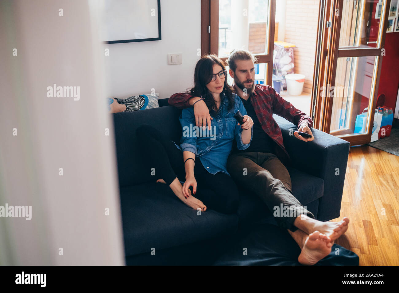 Young Beautiful Couple Sitting Couch Indoor At Home Watching Tv