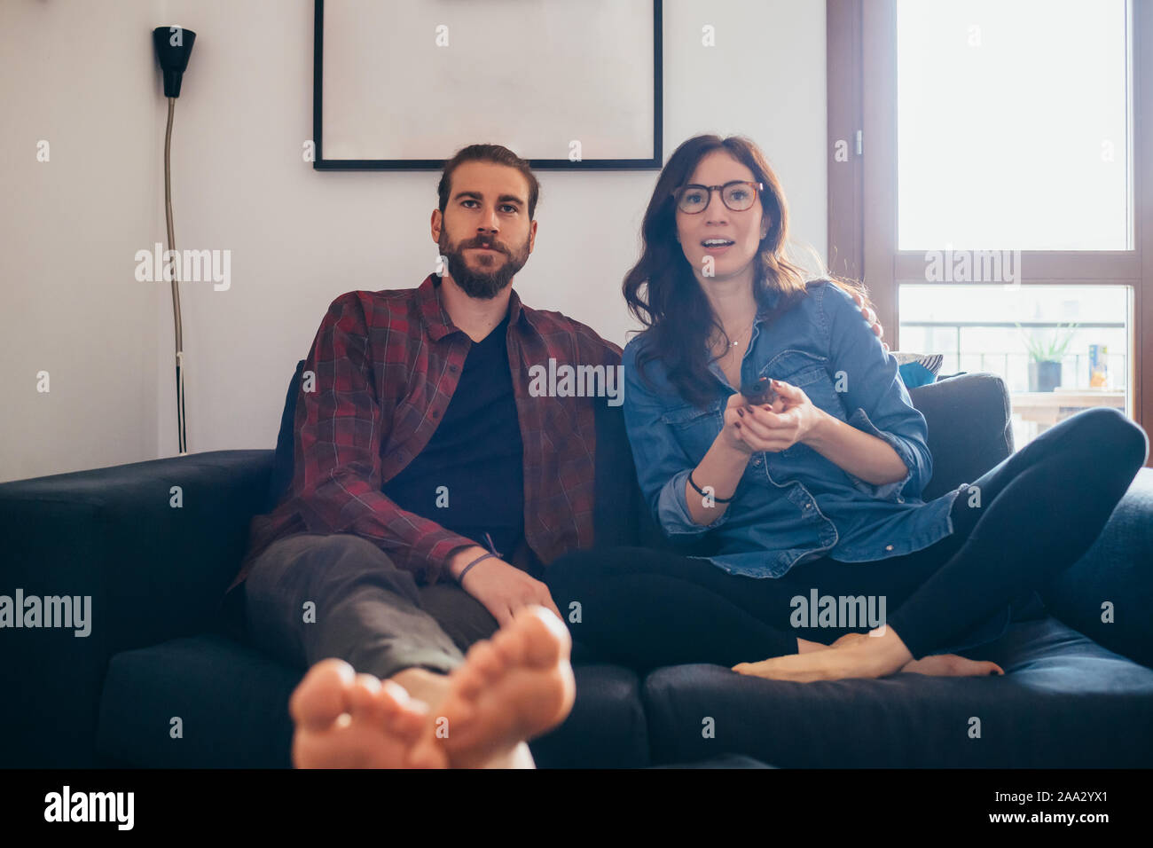 Young Beautiful Couple Sitting Couch Indoor At Home Watching Tv