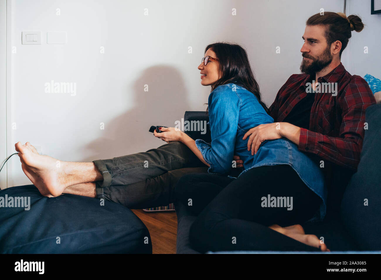 Young Beautiful Couple Sitting Couch Indoor At Home Watching Tv