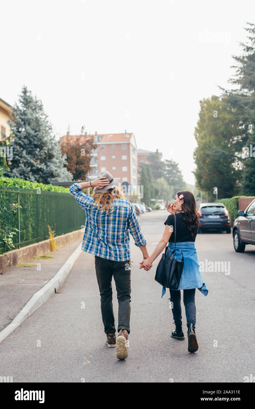 Happy beautiful couple in love walking throughfare holding hands ...