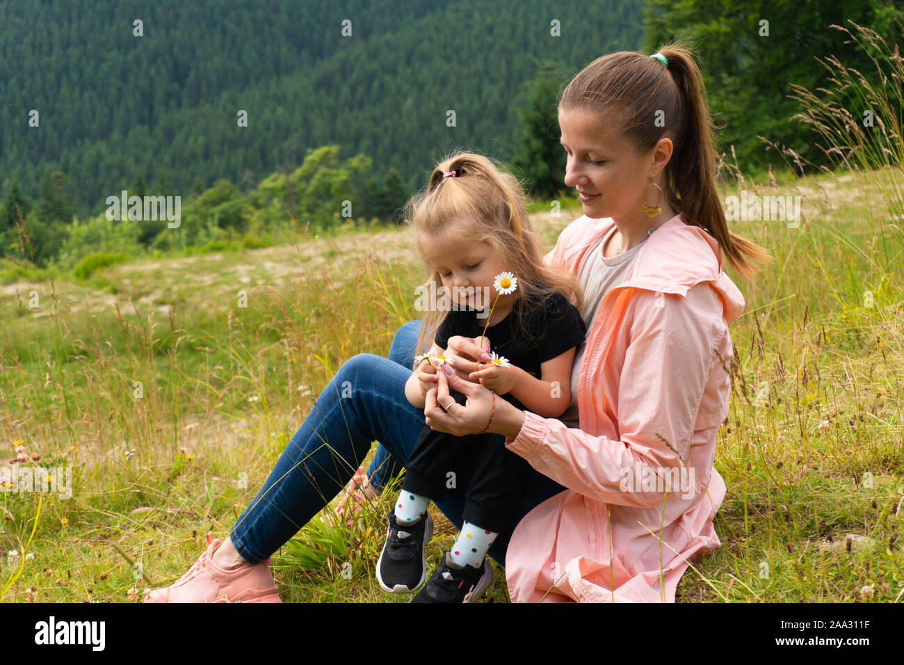 Woman and girl sitting on hill in mountains Stock Photo - Alamy