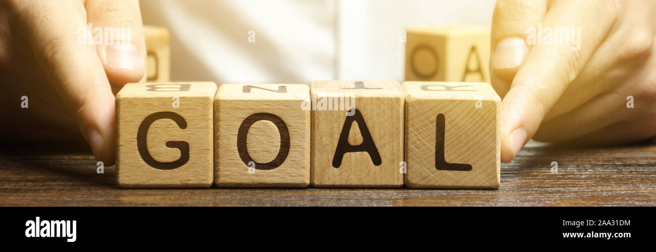 Businessman puts wooden blocks with the word Goal. The concept of achieving business goals. Reaching new heights. Execution of a business plan. Purpos Stock Photo