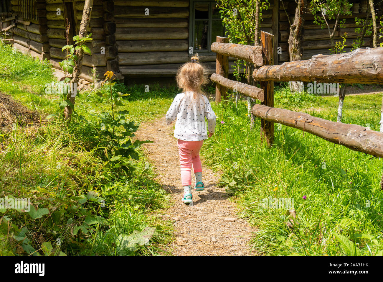 Little girl running to house at farm or village Stock Photo