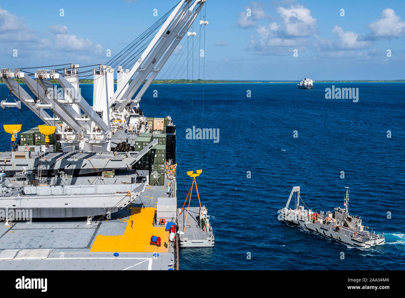 191112-N-CO914-1179  DIEGO GARCIA, British Indian Ocean Territory (November 12, 2019) Sailors aboard a warping tug approach an Improved Navy Lighterage System (INLS) Power Module being offloaded by a crane aboard Military Sealift Command Bob Hope-class roll-on roll-off vehicle cargo ship USNS Seay (T-AKR 302) during an INLS training mission. Navy Cargo Handling Battalion (NCHB) 1, NCHB 8, NCHB 11, NCHB 13, Assault Craft Unit (ACU) 1 and Amphibious Construction Battalion (ACB) 1 are participating in the INLS training mission under the direction of Commander, Task Force (CTF) 75 in preparation f Stock Photo
