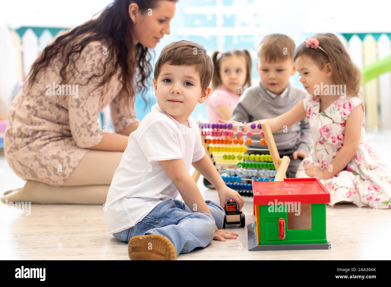 Preschool teacher and group of children in kindergarten Stock Photo