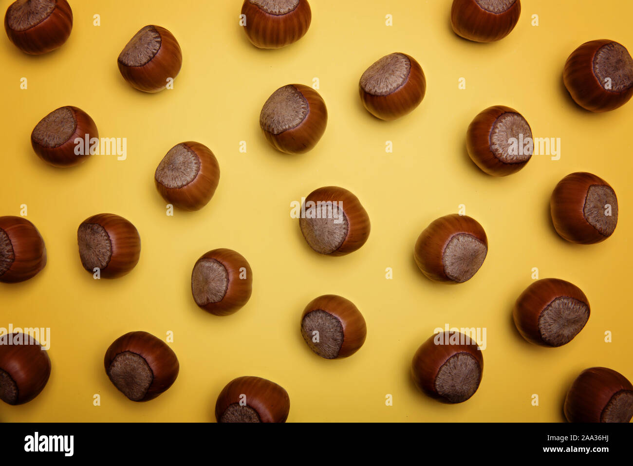 Unpeeled hazelnuts on a yellow background. Flatley. Copy space. Stock Photo