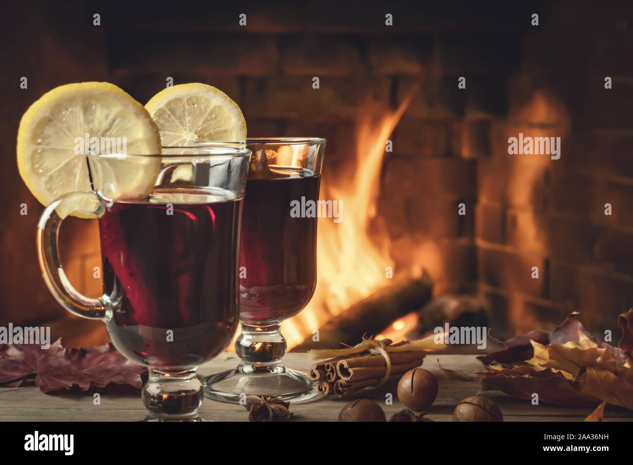 Two glasses of mulled wine on a wooden table in front of a burning fireplace. Stock Photo