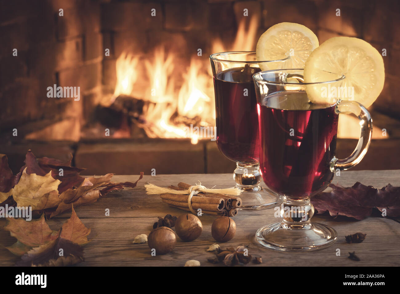 Two glasses of mulled wine on a wooden table in front of a burning fireplace. Stock Photo