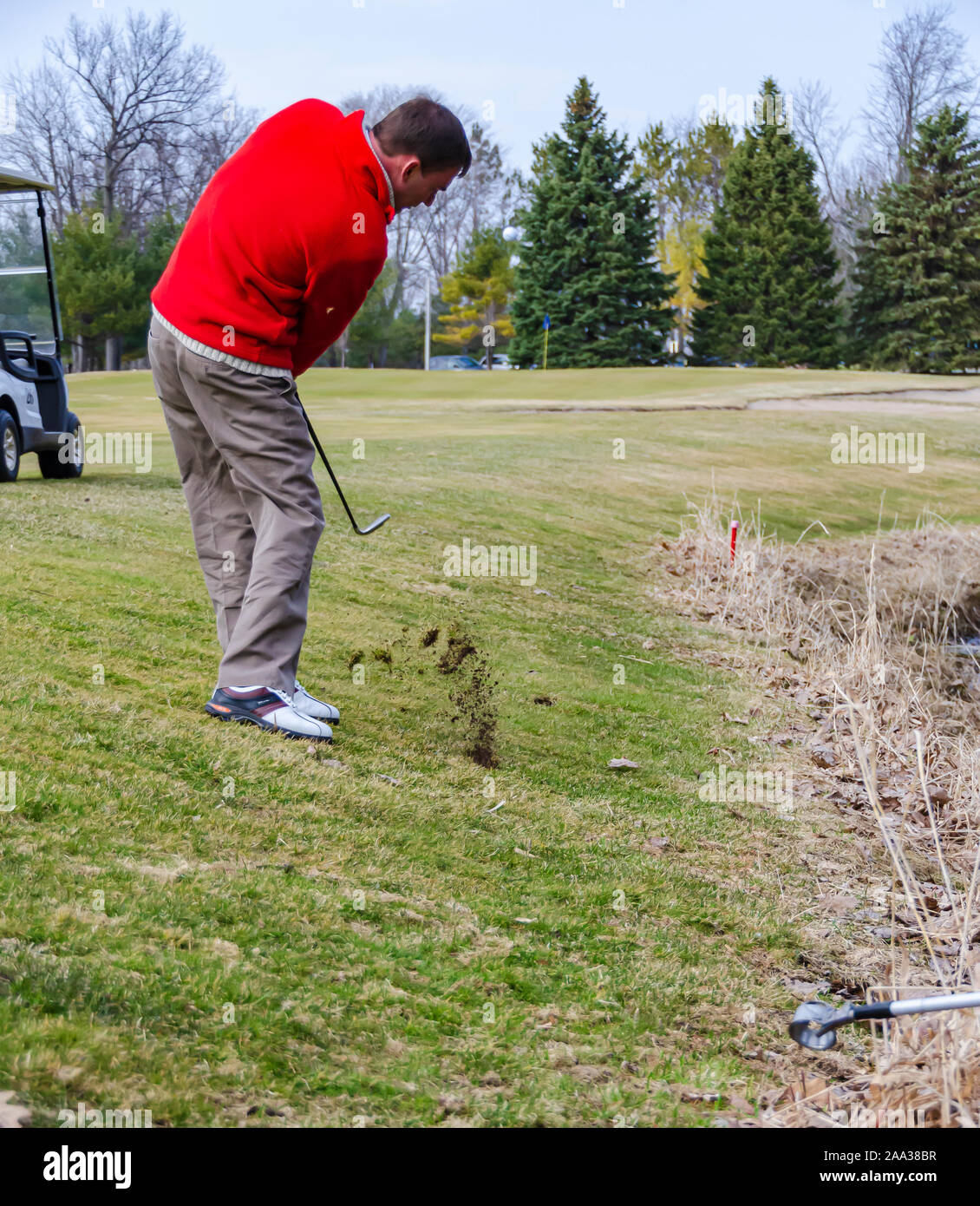 A golfer chipping the ball from the rough towards the green with an iron. Stock Photo