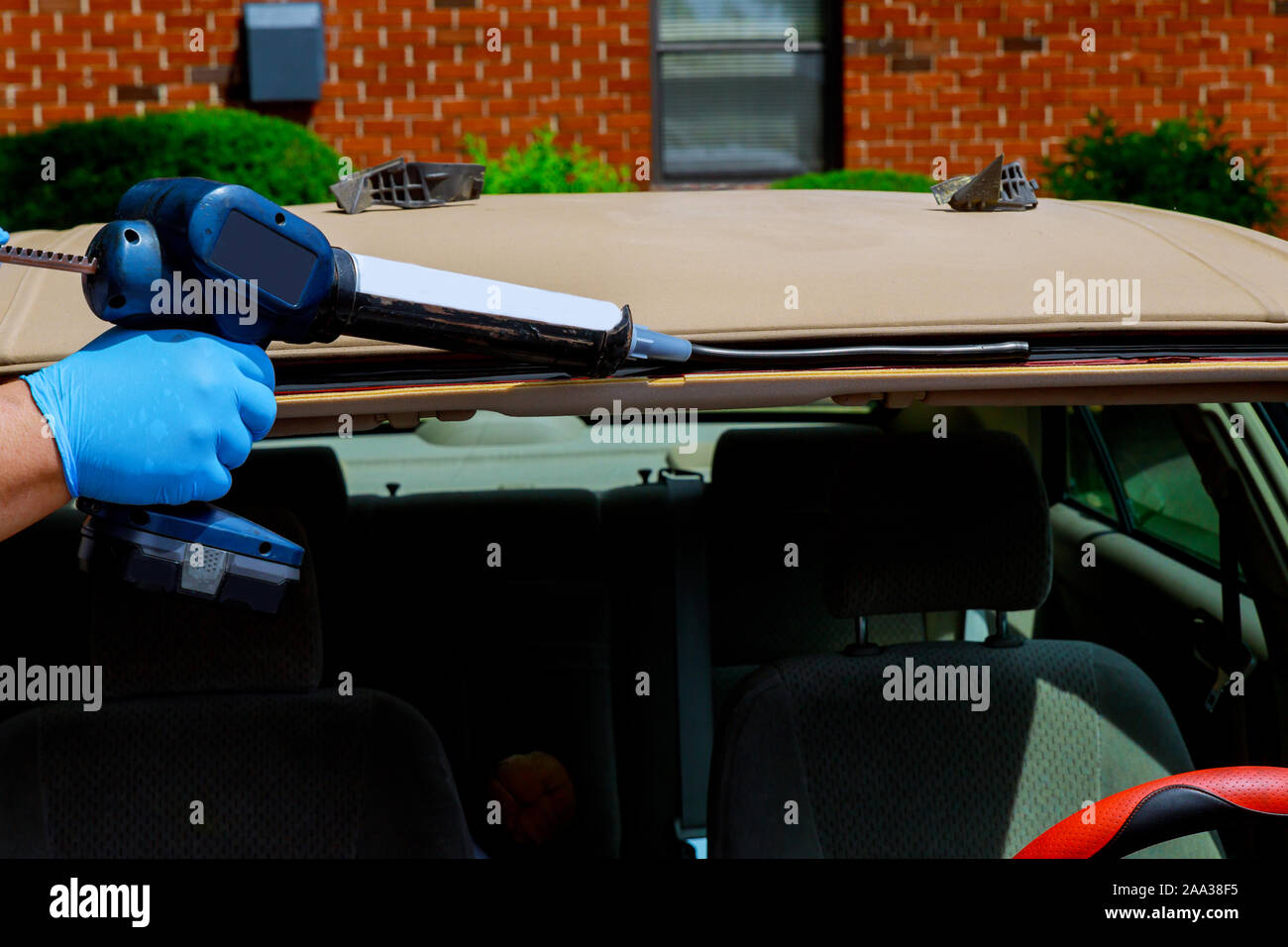 Automobile windshield replacement man using silicone tools to fix special workers replacing windshield Stock Photo