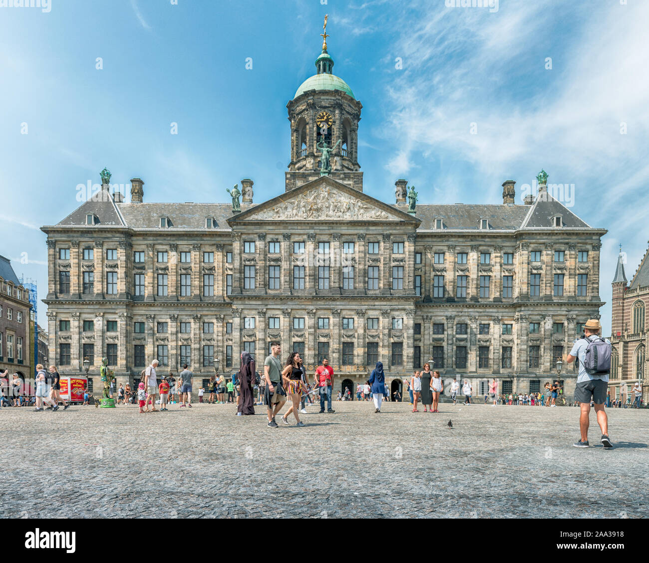 Amsterdam, Dam Square, the Netherlands 07/27/2019, Palace on the Dam Square in the summer, blue sky, people walking on the street Stock Photo