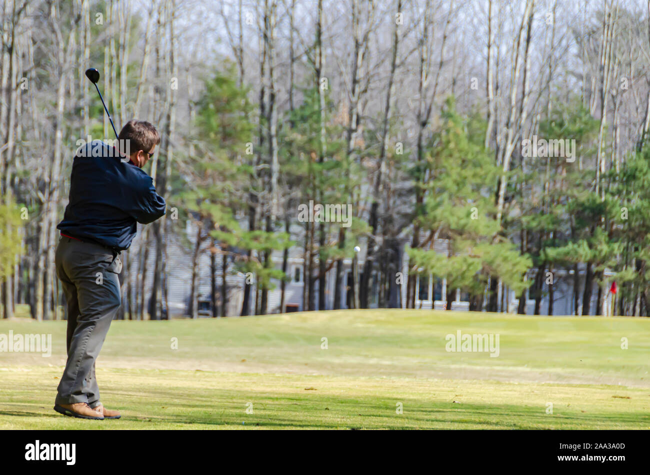 A golfer hitting the golf ball towards the putting green. Stock Photo
