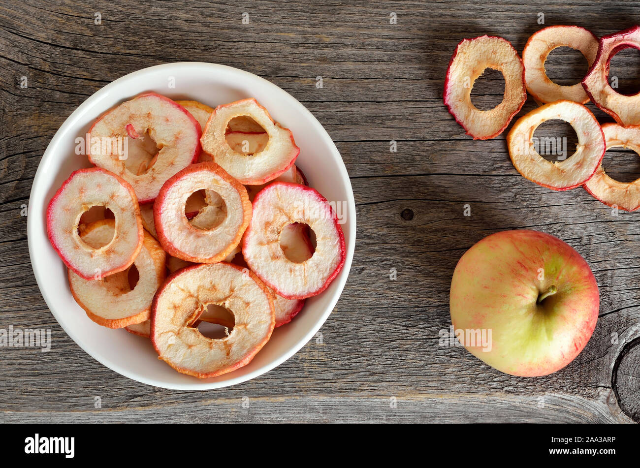 Dehydrated apples chips in wooden bowl on a wooden table, top view Stock Photo