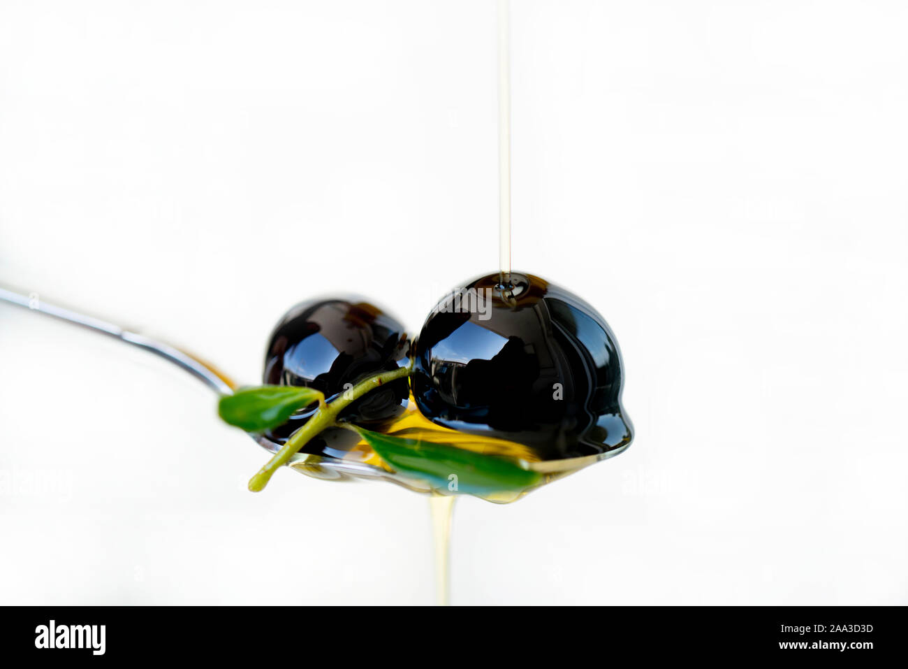 Olive oil over two olives branch in a spoon Stock Photo - Alamy