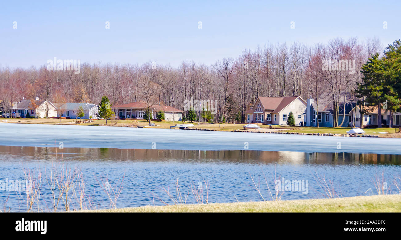 Houses on the banks of a thawing lake in upper Michigan, USA. Stock Photo