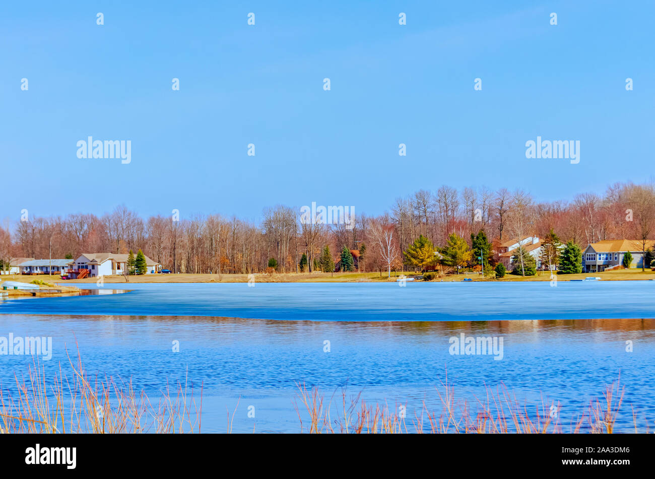 Houses on the banks of a thawing lake in upper Michigan, USA. Stock Photo