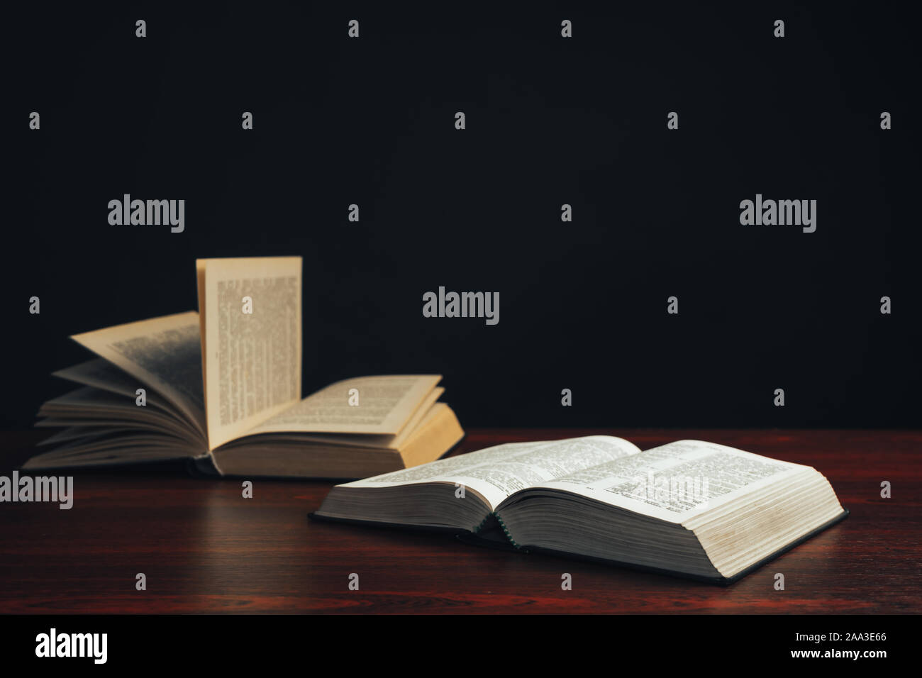 Open bible on a  red wooden table. Beautiful black background. Stock Photo